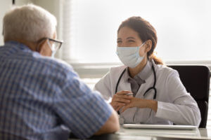 An elderly man sitting down with the best spine surgeons in Colorado Springs to discuss his treatment options.