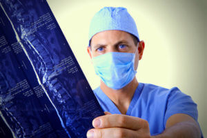 Dr. in scrubs reading and MRI of a spine.