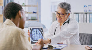 A female doctor showing a female patient the brain scan results on a tablet.