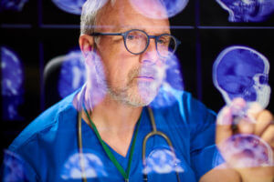 Image of a male tumor surgeon analysing brain scans for brain cancer tumors.