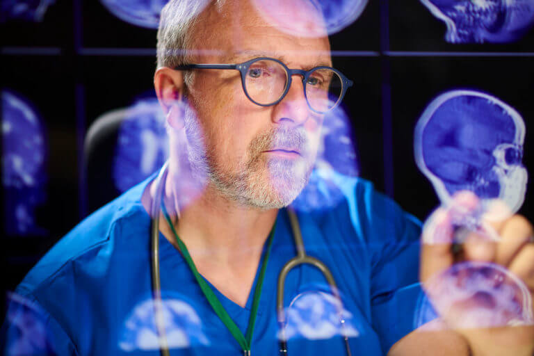 Image of a male tumor surgeon analysing brain scans for brain cancer tumors.
