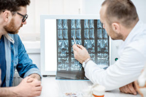 A top spine surgeon in Aurora, CO, explaining X-ray images of a patient's spine to the patient.