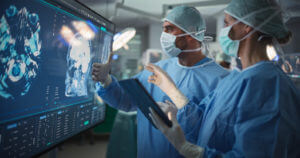 Image of a female and male Surgeons Reviewing Brain Scans for Tumors in a Dimly Lit Operating Room.