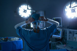 A female neurosurgeon wearing a surgical mask in the operating room is preparing for spine surgery.