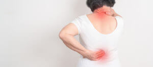 Elderly woman having back and neck pain caused by degenerative disc disease.