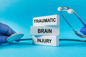 Stethoscope and Traumatic brain injury text on white notepads, blue background.