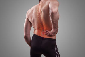 A man holds his back in pain from scoliosis.